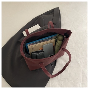 Top view of spacious burgundy tote bag interior with books, phone, and folding umbrella
