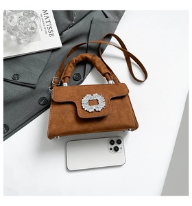 Brown suede handbag size comparison with smartphone and elegant rhinestone buckle detail