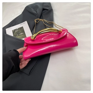 Close-up of rose red patent leather bag with a distinctive curved gold metal handle