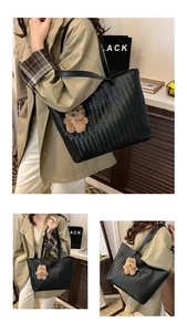 Detail view of large black woven tote bag featuring a cute brown plush bear charm