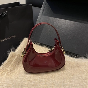 Chic burgundy patent leather crescent shoulder bag with elegant gold hardware buckles
