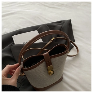 Detail of color-block bucket bag showing woven texture, leather trim and gold twist lock