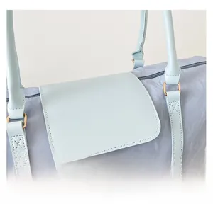 Macro shot of light blue travel bag featuring textured fabric and faux leather details