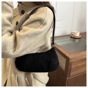 Detail of black faux suede underarm bag with metal zipper and slim shoulder strap