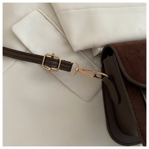 Detail of dark brown crossbody bag featuring mixed textures and golden hardware