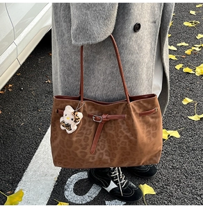Close-up of leopard print tote bag with plush charm on ginkgo leaf street background