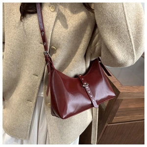 Détail du sac sous le bras en cuir verni bordeaux avec œillets argentés et fini lisse