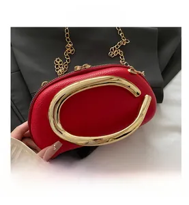 Macro shot of red pebble leather handbag with oversized gold ring handle and gold chain