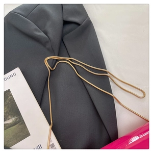 Close-up of hot pink shoulder bag with a gold snake chain on a grey blazer