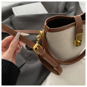 Detail shot of canvas bucket bag featuring premium leather trim and golden metal clasp
