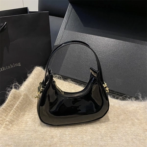 Modern black patent leather hobo bag with glossy mirror finish and gold hardware accents