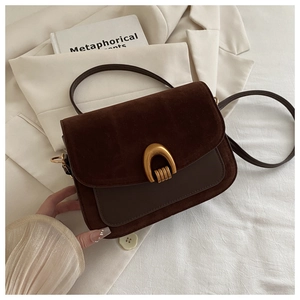 Close-up of brown suede crossbody bag with vintage gold U-shaped buckle detail
