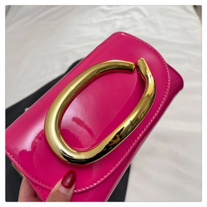 Detail of rose pink patent leather bag with a large polished gold circular metal handle