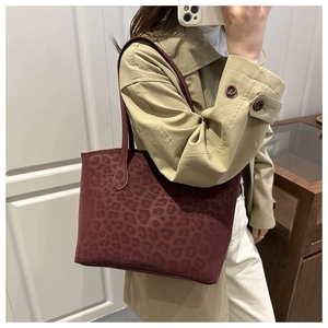 Detail of burgundy leopard print tote bag texture and dual shoulder straps on a model
