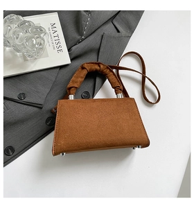 Close-up of caramel suede handbag with unique ruched handle and silver metal studs