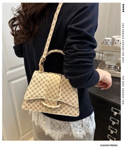 Detail view of beige geometric printed handbag with golden hardware and leather buckle