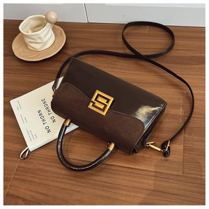 Detail of vintage crossbody bag with brown matte flap, black glossy base and gold buckle