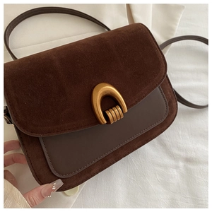 Detail of vintage dark brown suede crossbody bag with elegant gold arch metal buckle