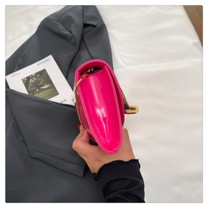 Close-up of fuchsia patent leather handbag with gold chain and large metal ring clasp