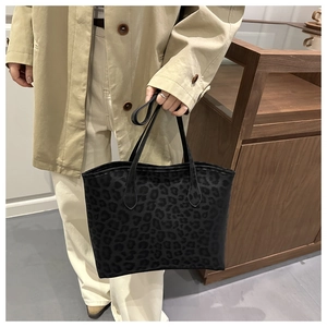 Detail of a large leopard print tote bag carried by a model in a beige coat for commuting