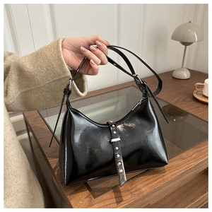 Détail d'un sac hobo en cuir verni noir avec boucle argentée et finition brillante