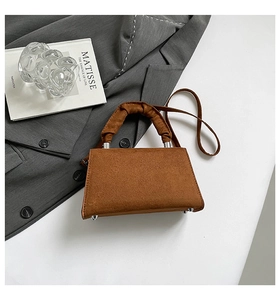 Detail of a brown suede handbag with a unique ruched handle and silver hardware