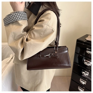 Detailed view of dark brown glossy leather underarm bag with metal buckle and strap