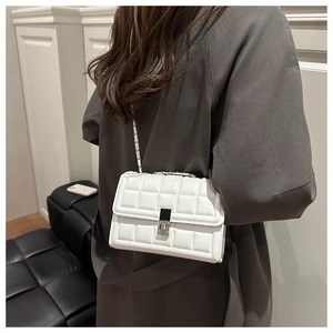 Detailed close-up of white quilted crossbody bag with silver chain and metal clasp