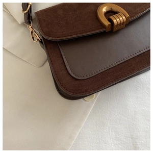 Detailed shot of retro gold U-shaped buckle and suede leather stitching on brown bag