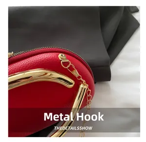 Detail of red litchi leather evening bag with golden hardware hooks and chain attachments