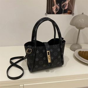 Minimalist black tote bag with floral print, gold clasp, and adjustable shoulder strap