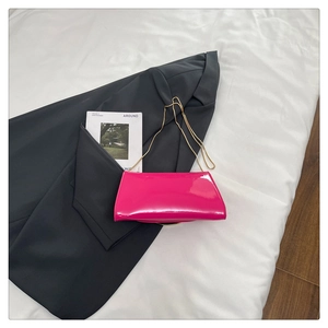 Detailed close-up of glossy fuchsia patent leather crossbody bag with gold chain strap