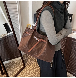 Detail of leopard print tote bag with brown leather straps and metallic buckle accent