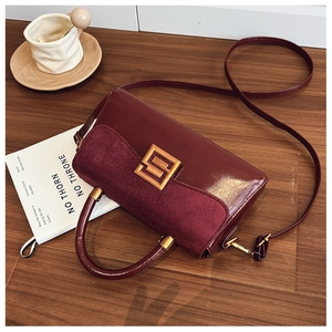 Detail view of burgundy matte leather crossbody bag with elegant gold metal buckle hardware
