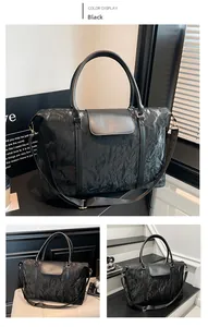 Close-up of black glossy crinkled fabric travel bag with dual handles and strap