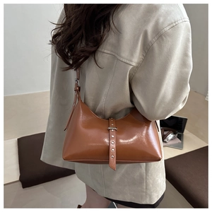 Vue détaillée du sac hobo en cuir marron avec rivets argentés porté par le modèle