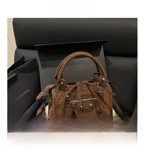 Detail of brown suede motorcycle handbag with silver rivets and long fringe tassels in box