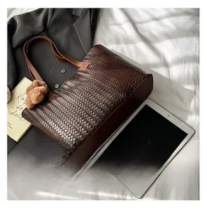 Detail of dark brown woven tote bag texture with plush bear charm on white fabric