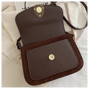 Detail of dark brown crossbody bag with magnetic closure and front pocket on books