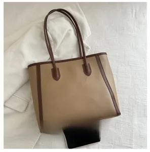 Detailed size comparison of a khaki tote bag next to a smartphone on a white texture