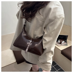 Détail d'un sac hobo en cuir brillant marron foncé avec des rivets argentés chic