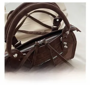 Detail of smooth metal zipper and long leather tassels on brown vintage biker bag