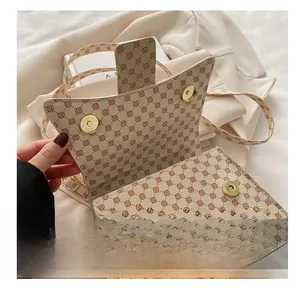 Detail of dual gold magnetic buckles and floral pattern on cream leather crossbody bag