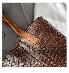 Close-up of the intricate woven leather texture and fine stitching on a dark brown tote bag