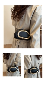 Close-up of black textured leather handbag with a large gold C-shaped metal buckle