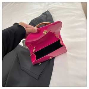 Detail of fuchsia patent leather handbag with gold ring handle and magnetic closure