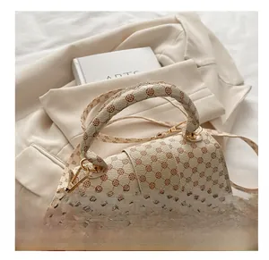Detail of beige printed shoulder bag with clover patterns and golden metal hardware