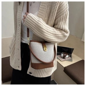 Detail of vintage canvas and brown leather bucket bag with gold clasp shown on a model