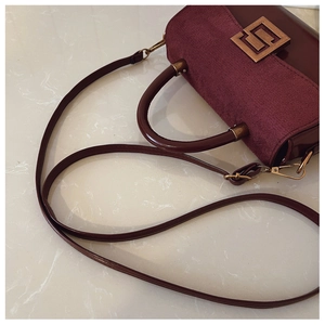 Detail of burgundy matte leather crossbody bag with elegant gold geometric metal buckle