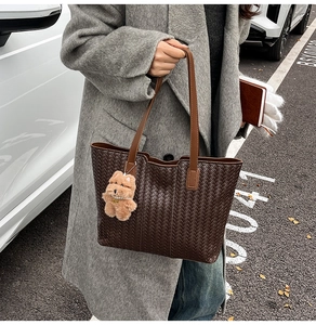 Detail of dark brown woven tote bag with smooth leather strap and cute dog plush charm